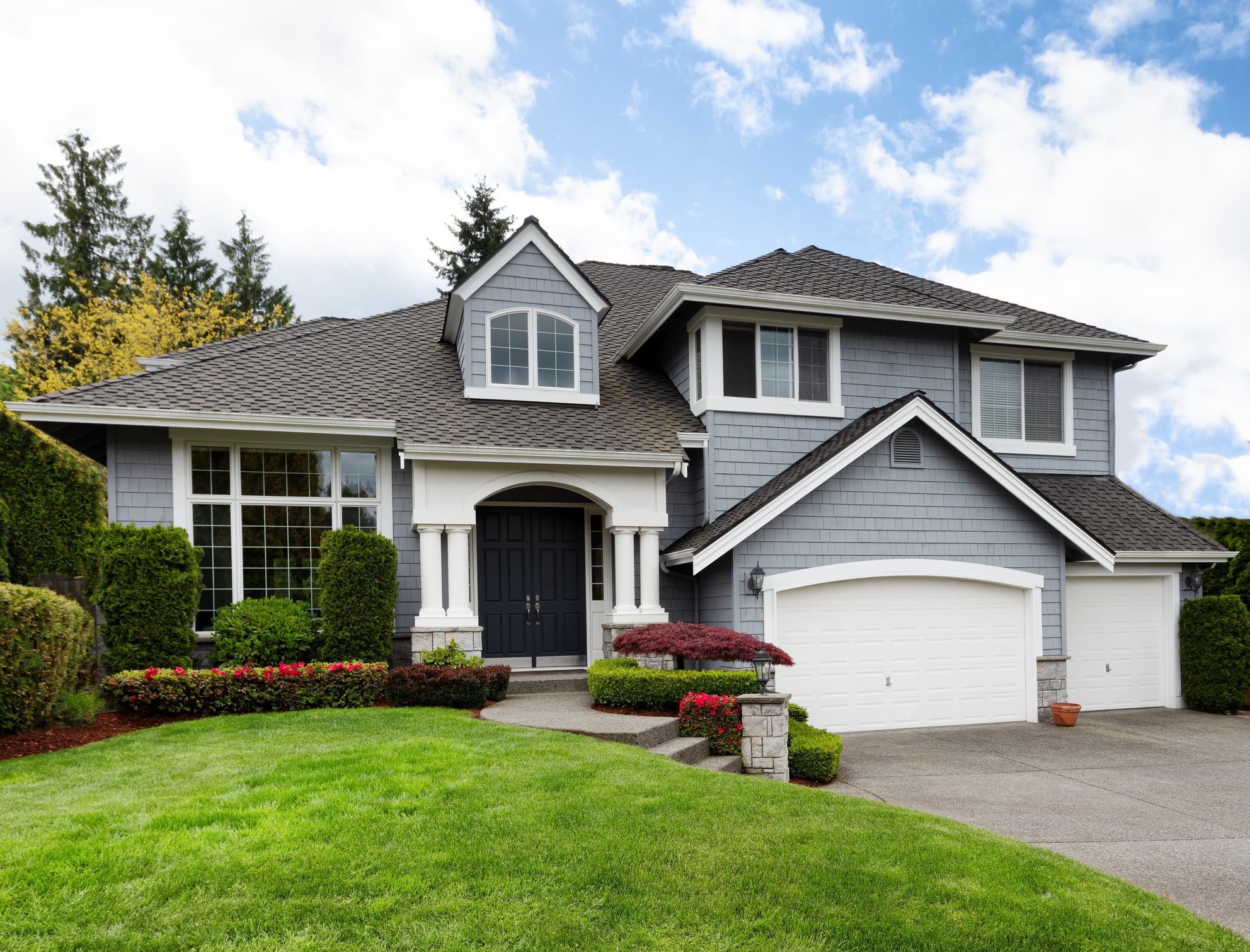 Large gray home exterior showcasing professional white trim painting.