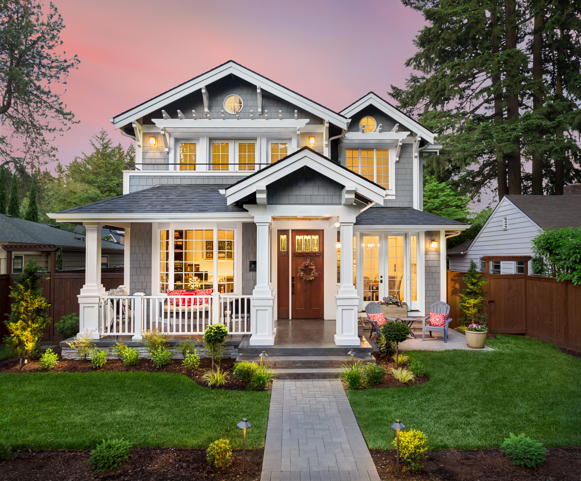 Grey craftsman home exterior with white trim and sunset sky